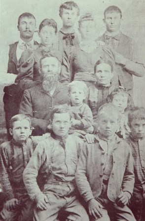 black and white photograph of the Behunin family. There are 13 people in the photo.