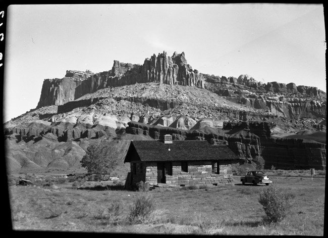 Small stone building in rocky landscape, with dramatic spiked  cliffs.