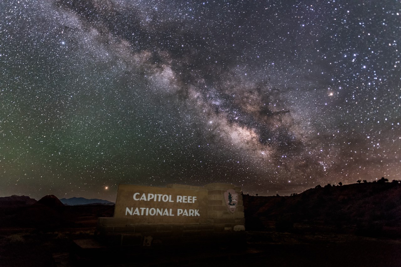 Band of sparkling white stars above a stone entrance sign for Capitol Reef National Park.