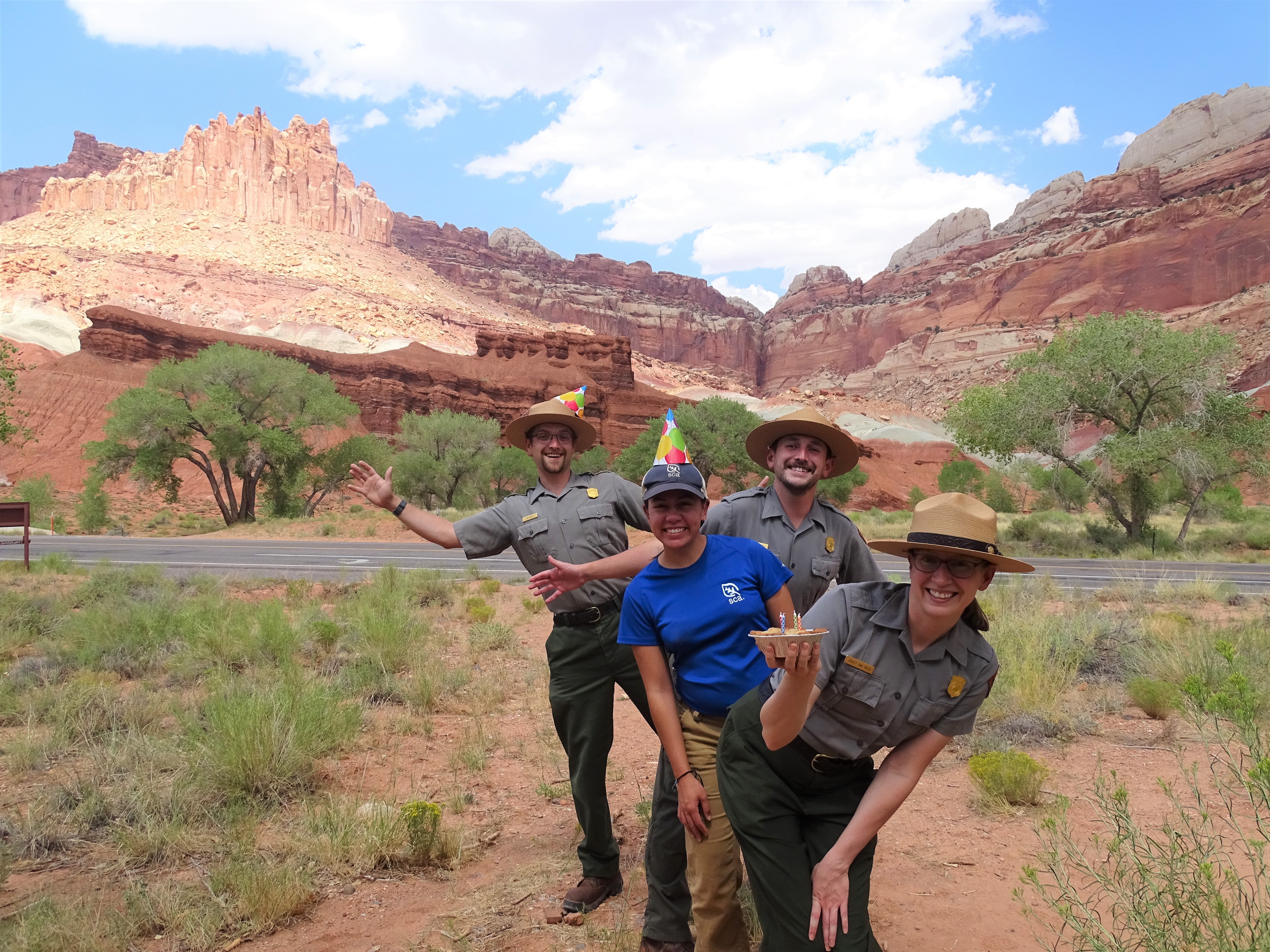 Four rangers stand in a line. One holds a pie with birthday candles