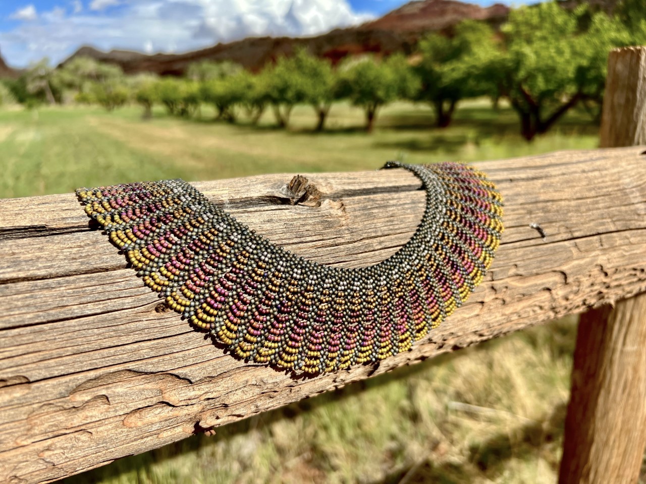 Bentonite by Jennifer Alexander Fritz Multicolored beaded necklace on a wooden fence