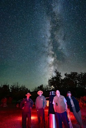 Capitol Reef staff stand around a telescope with Milky Way visible overhead.