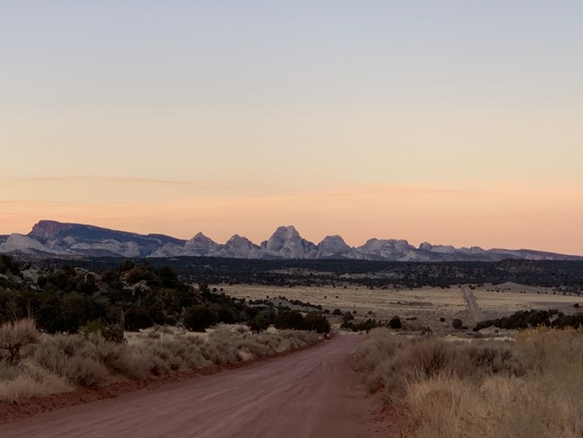 Dirt road with views of pale rock formations and a sunset sky.
