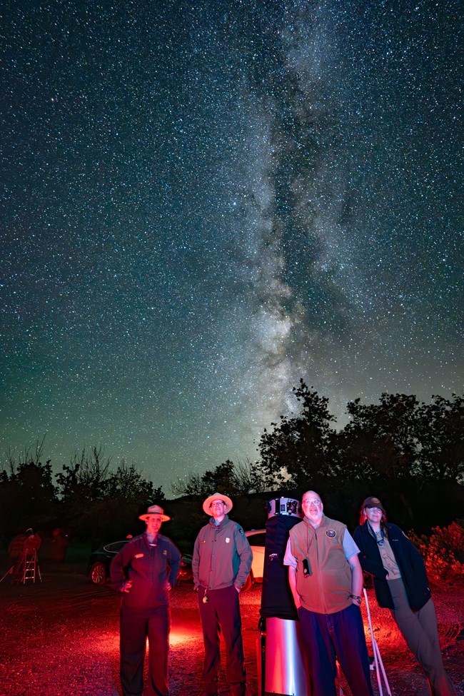 Capitol Reef staff stand around a telescope and the Milky Way.