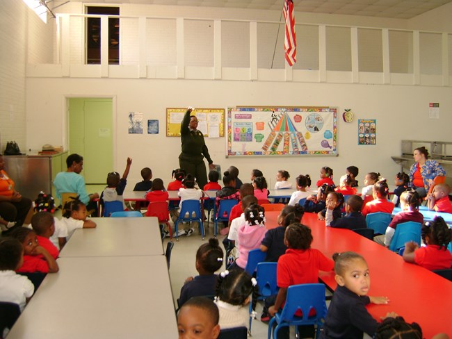 Ranger stands before classroom of young kids.
