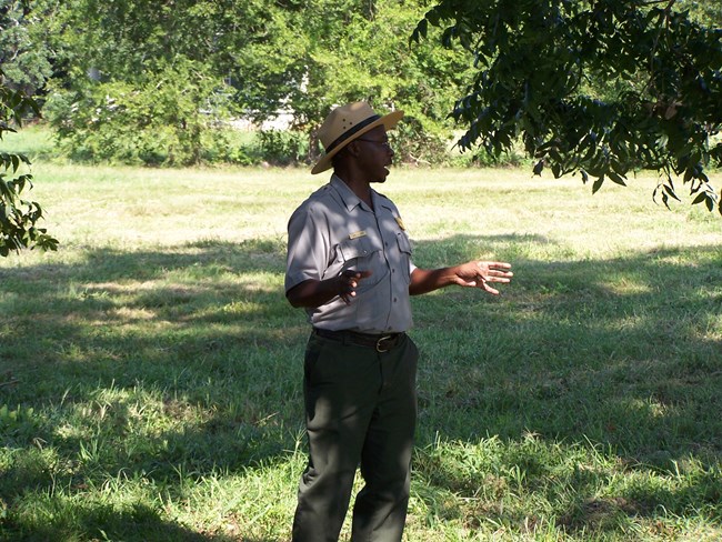 A park ranger speaking, in the grass at Oakland Plantation