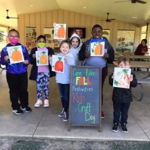 Children stand showing off the pumpkins they painted on canvas.