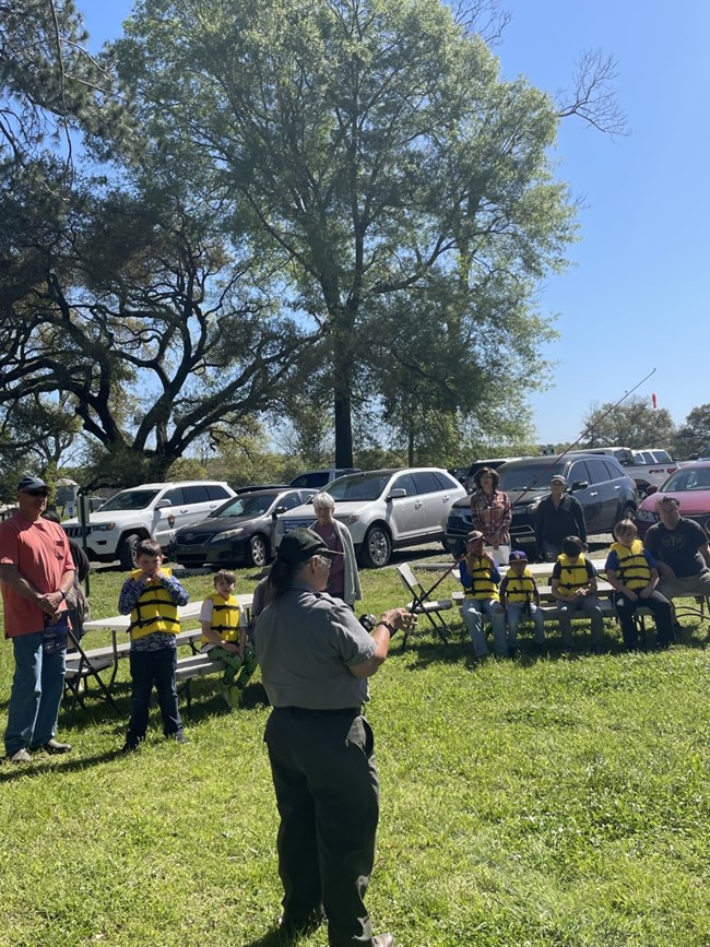Kids in live vests sitting on bench in front of park ranger