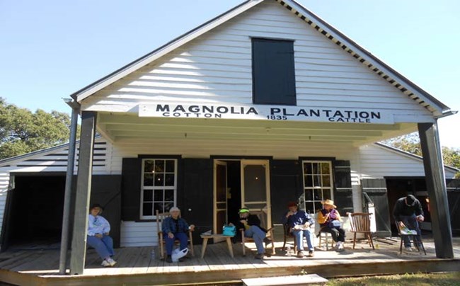 Visitors eat lunch while sitting in rocking chairs on the front porch of Magnolia Store.