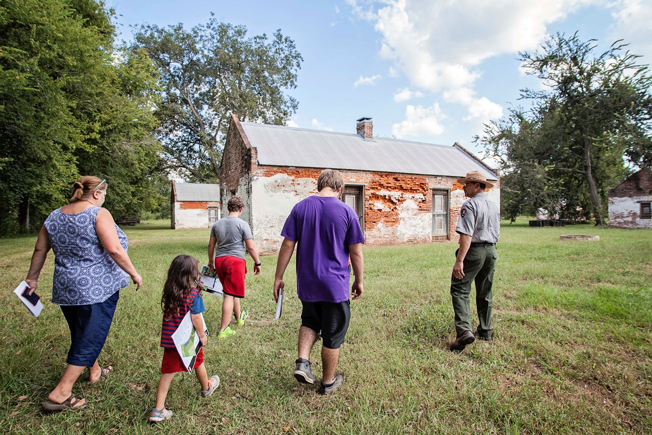 Ranger Rodney Meziere walks with visitors to the brick slave/tenant cabins at Magnolia Plantation