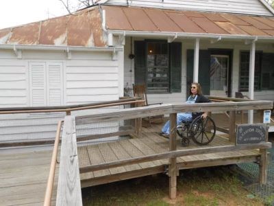 Woman in a wheelchair is traveling down the plantation store ramp.