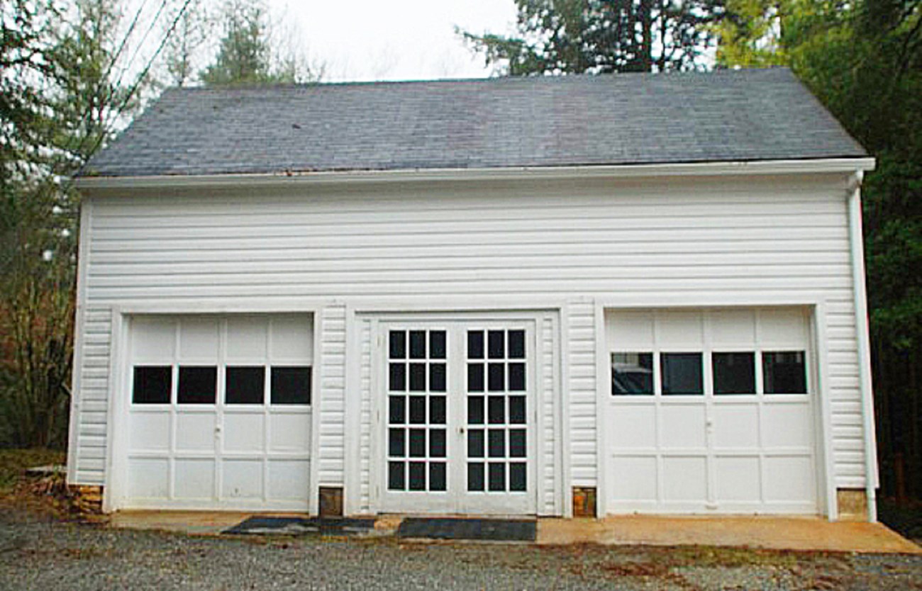 Image of front of house garage Image of front of house garage, a single story white painted building with 2 garage doors and a french door in the middle