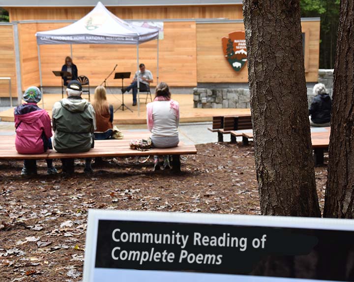 Visitors sit in audience listening to people read from Carl Sandburg's Complete Poems