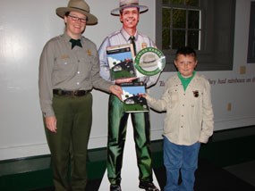 Park Ranger stands with the first Junior Ranger in the park's history.