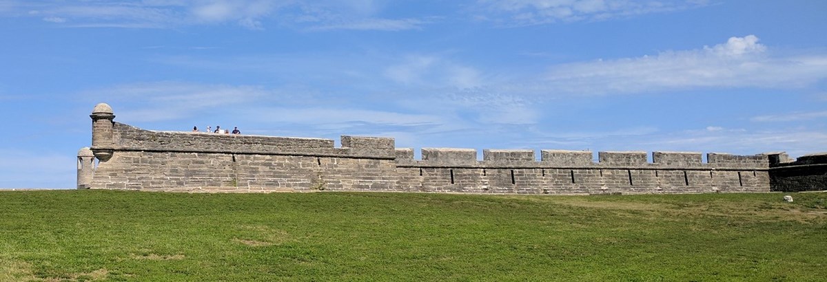 Western wall of Castillo. Sky above, grass below.