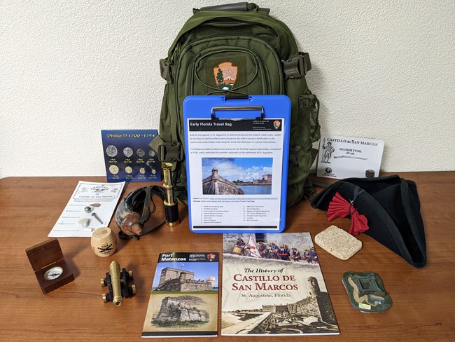 A green NPS backpack with a book and hands-on materials.