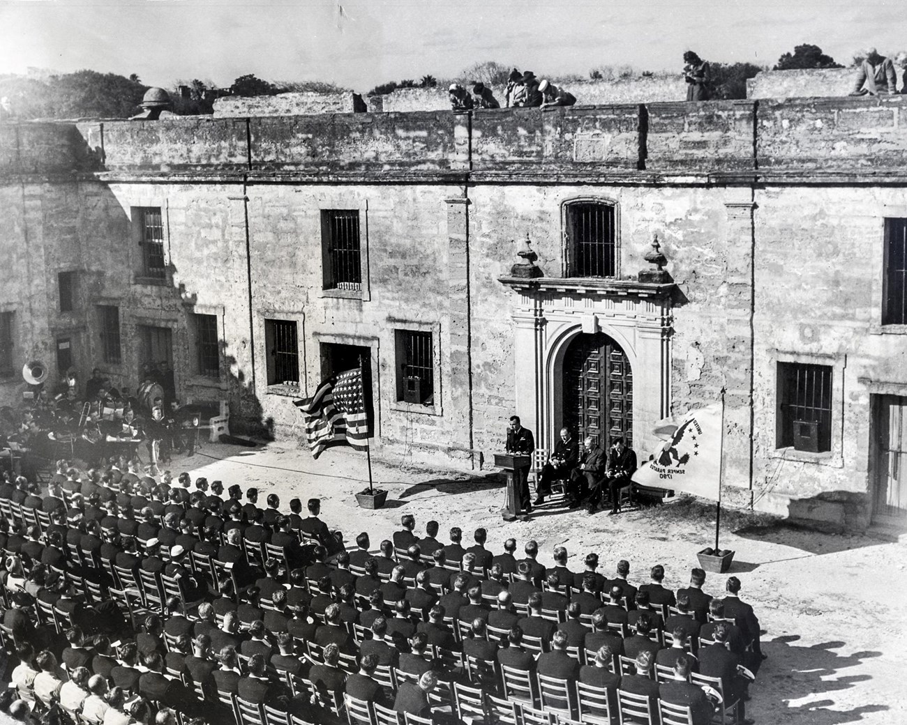 Coast Guardsmen sit in chairs in the Castillo's courtyard for their graduation ceremony.