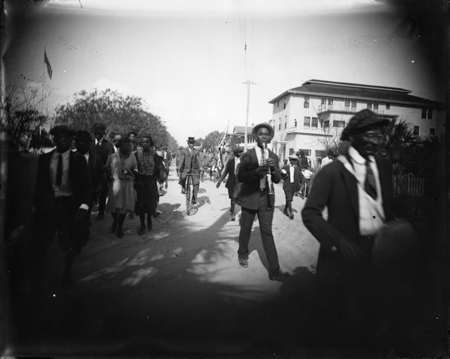 African Americans marching in parade and playing instruments.