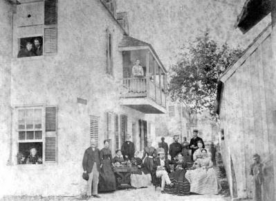 Black and white photograph of a group of men and women outside the boarding house.