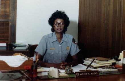 Modern photograph of Martha Aikens at her desk at Castillo NPS Headquarters.