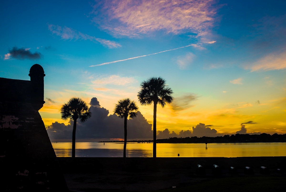Beautiful sunrise over the water with the southweast bastion and palm trees.