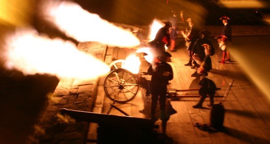 Spanish soldiers fire two three-pounder field pieces at night.
