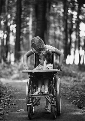 Circa 1976 photo of two children chatting on the Spicebush Trail. One child is in a wheelchair, and the other stands behind the wheelchair.
