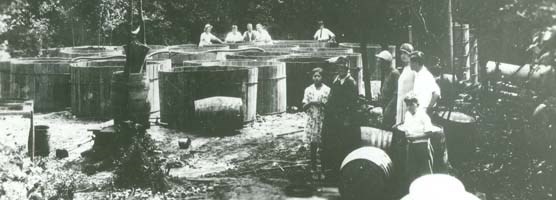 A group of people standing around large wooden vats.