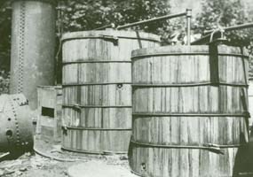 Large Wooden Vats with pipes on top and a large iron boiler in the background