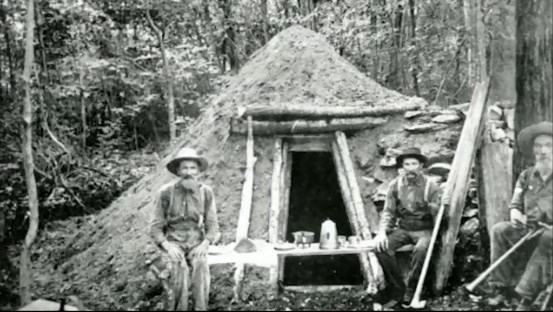 Three Colliers (Charcoal Makers) outside of a wood shack Three Colliers (Charcoal Makers) outside of a wood shack