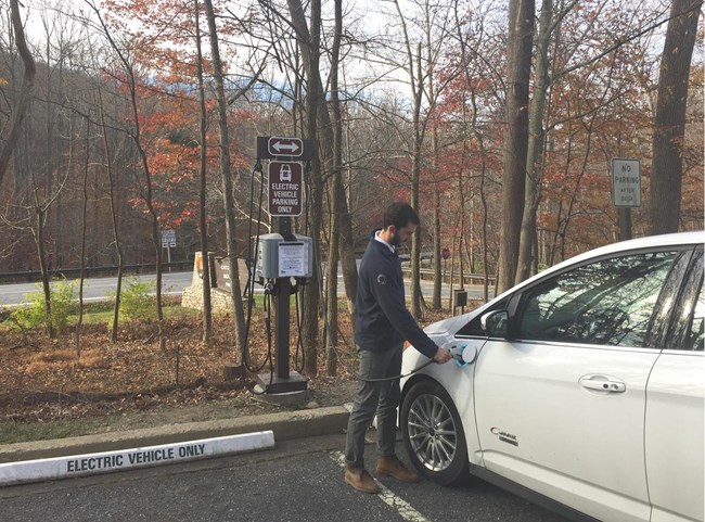 Person and car at electric vehicle charging station