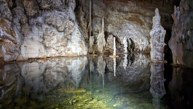 a pool of green colored water is surround by cave formations