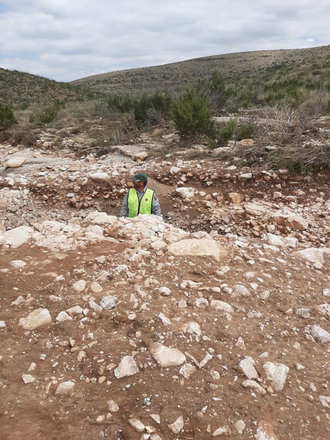 Photo of maintenance employee in road washout.