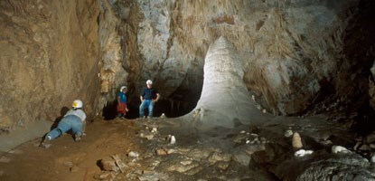 Photo of visitor climbing up to the large White Giant stalagmite.