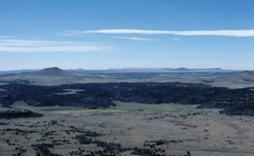 color photograph of mesa with mountain at left front and right back