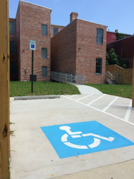 A blue wheelchair accessible logo painted onto the pavement in front of a historic house