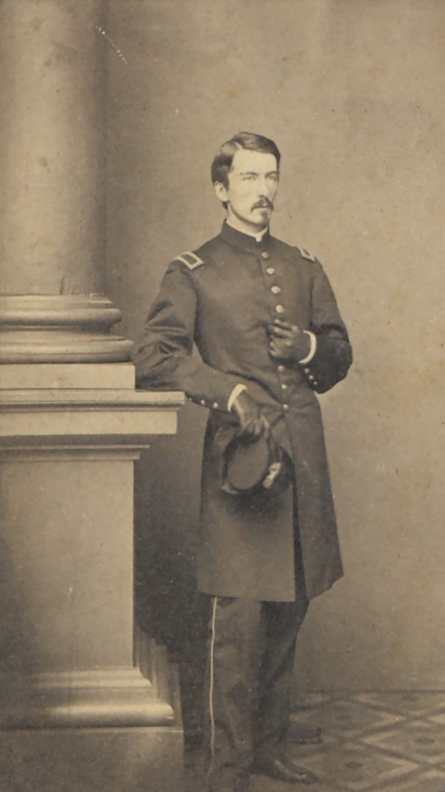 Henry A. du Pont, c. 1861 A young 1860s army officer stands next to a pillar for a full portrait photograph.