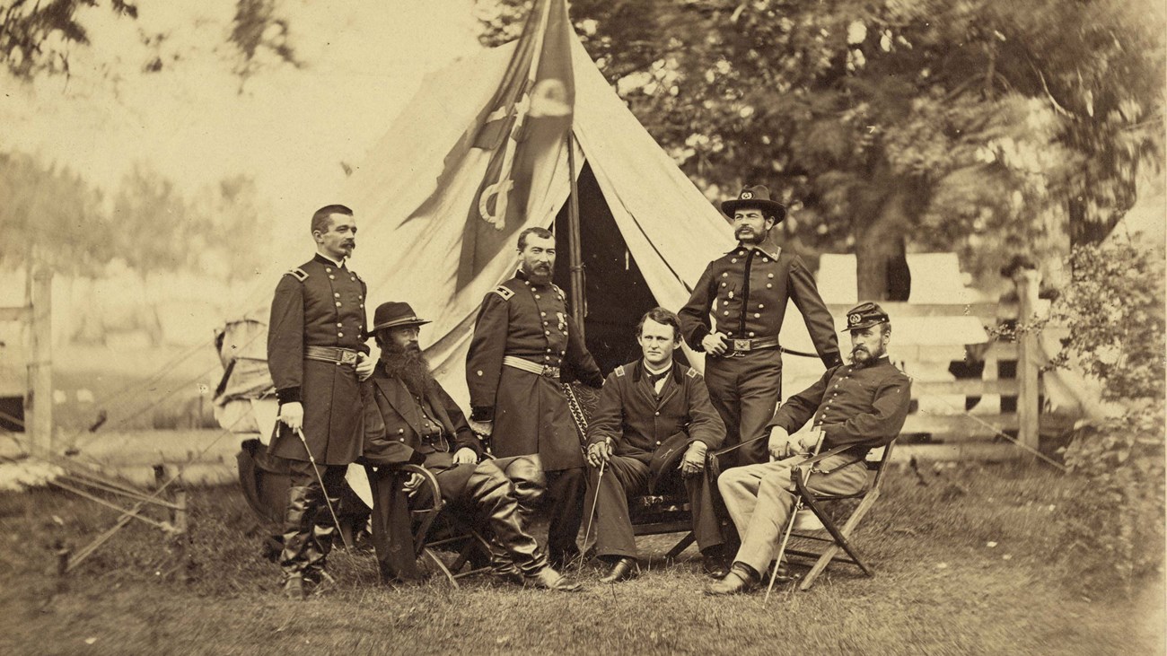 A general and five of his commanders pose outside a tent in an 1864 photo.