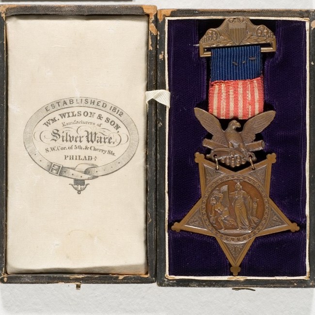A curatorial photo shows an army medal from a museum collection.
