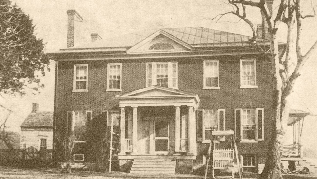 A sepia photo shows an antebellum style mansion with a brick façade and white trim.