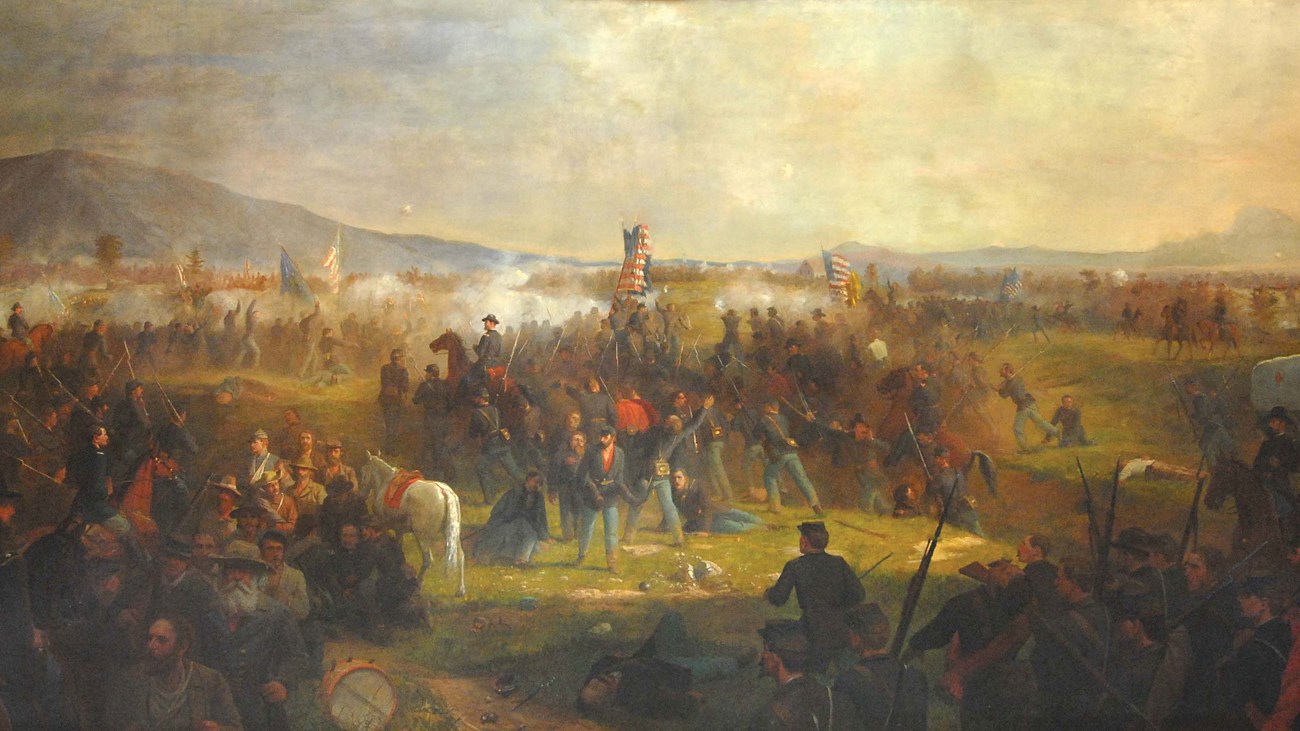 A painting richly colored with red and yellow depicts soldiers rallying to the U.S. flag in the midst of battle.