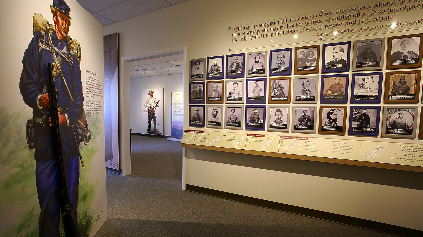 Indoor exhibits featuring a Civil War soldier and rows of framed photographs.