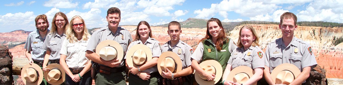 Group of park employees in NPS Uniform standing in front of red and orange cliffs. Group of park employees in NPS Uniform standing in front of red and orange cliffs.