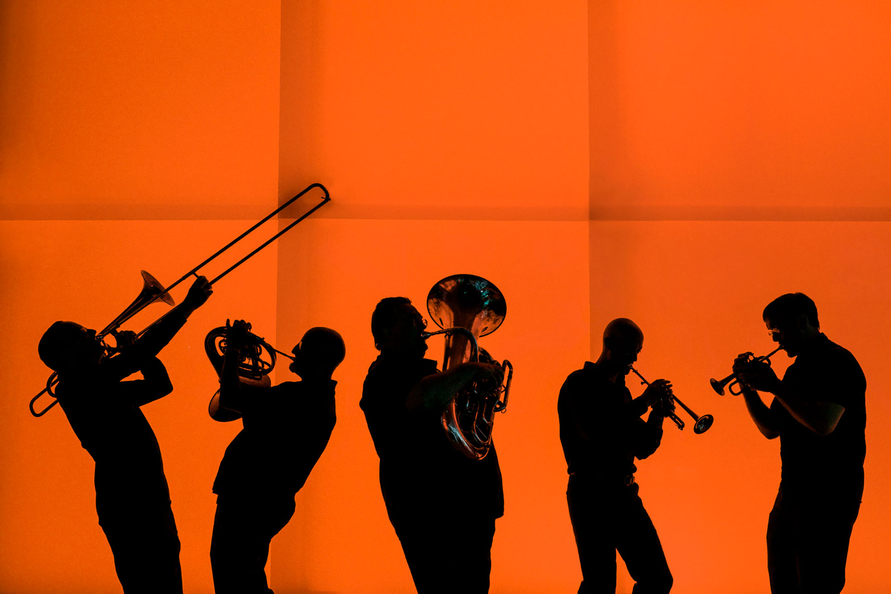Utah Symphony Performing At Cedar Breaks as Part Of “Great American Road Trip” Tour Brass musicians playing in front of an orange background.