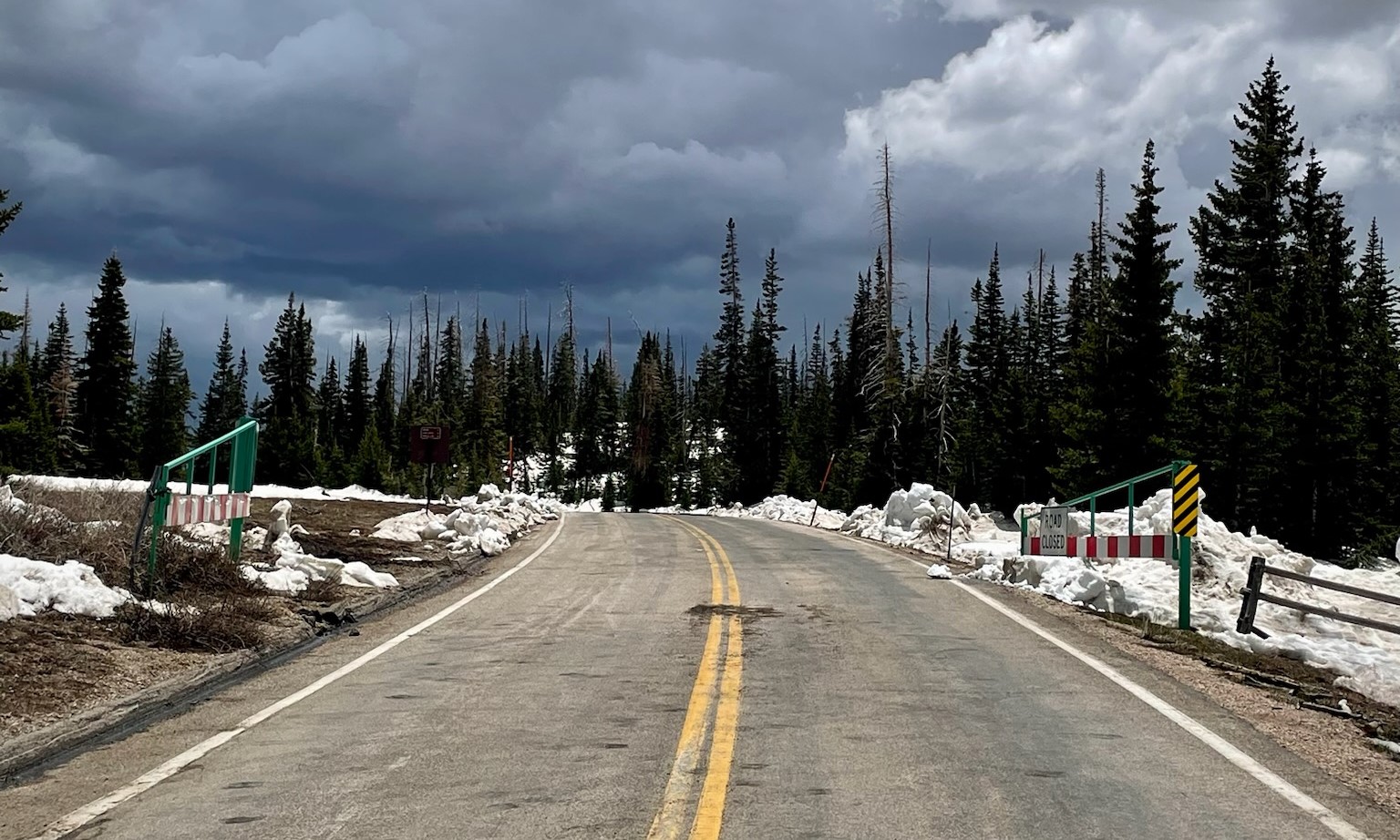 Open gates allow passage on a snow free road with stormy skies above Open gates allow passage on a snow free road with stormy skies above
