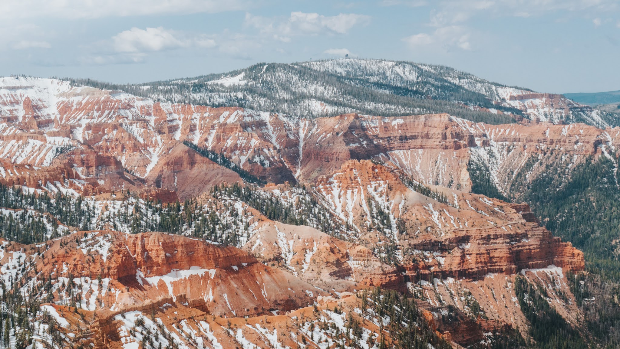 A view of a landscape of red cliffs with minimal snowpack.
