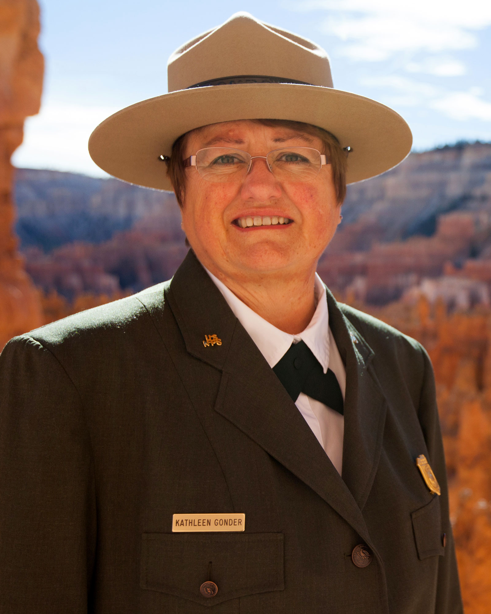 KathleenGonderHeadshot1 Head-shot of a woman wearing a NPS uniform, with orange cliffs in the background.
