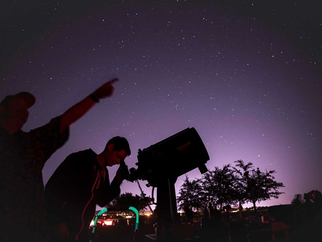 Two men looking through a telescope at the night skies. Two men looking through a telescope at the night skies.