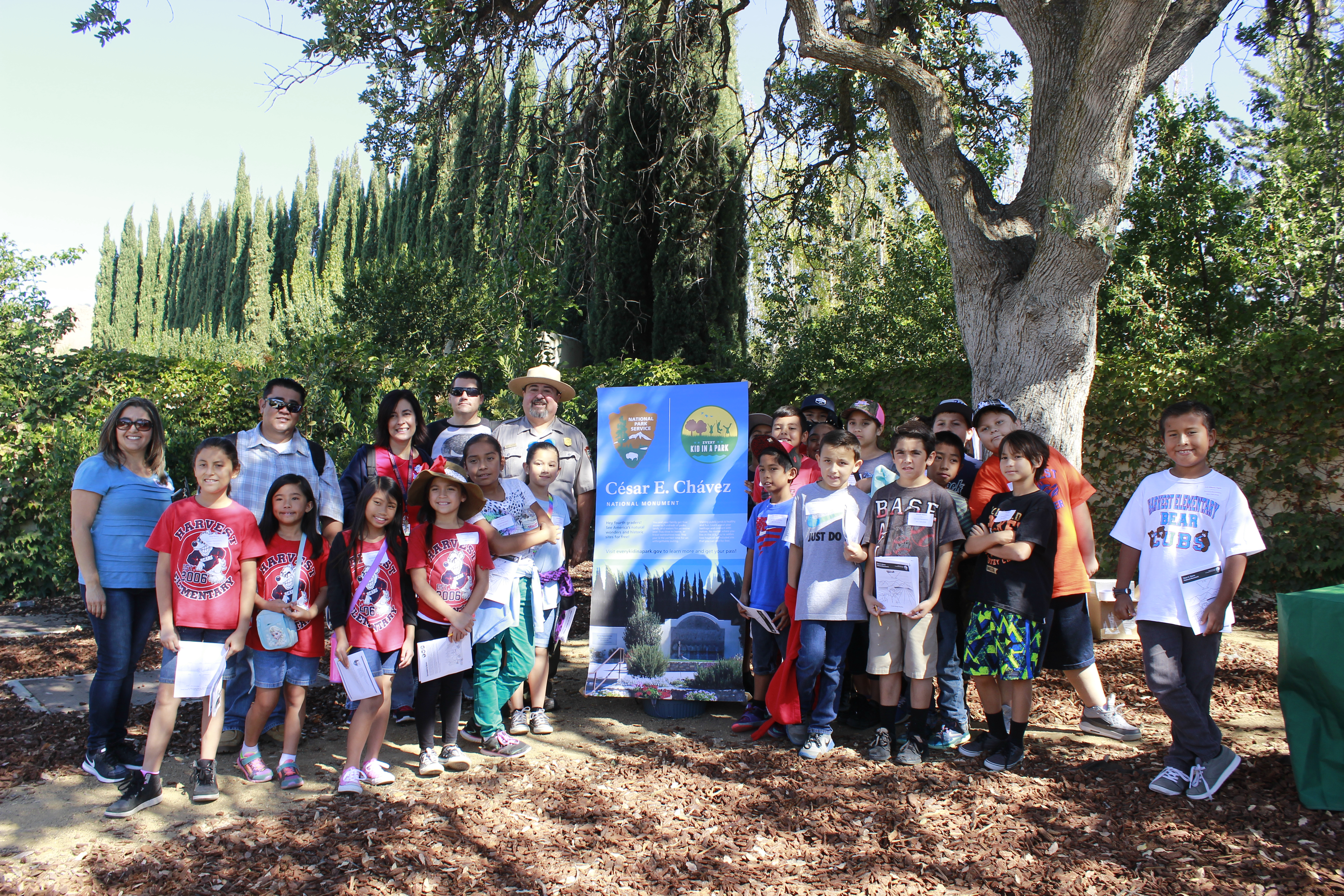 students, teachers and park superintendent pose under a tree