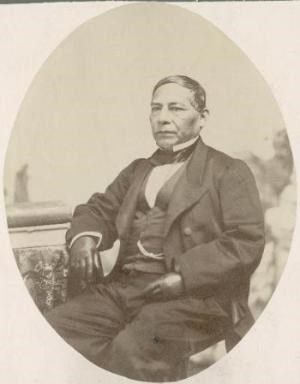 Oval portrait of man seated, wearing suit, vest, and gloves